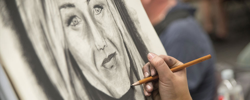 ICC Art student sketching a woman's face.